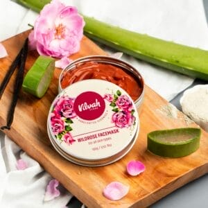 Flat lay of a wild rose face mask with aloe and rose petals on a cutting board.